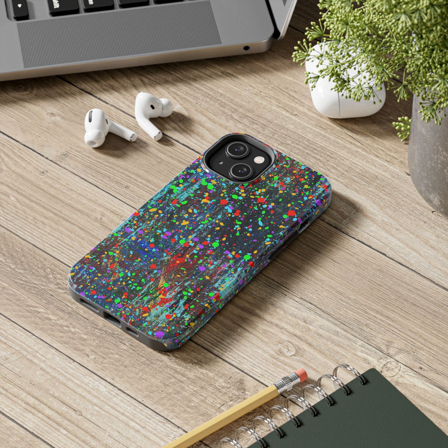 Printify colorful abstract drip paint phone case on wooden desk with laptop AirPods plant and notebook