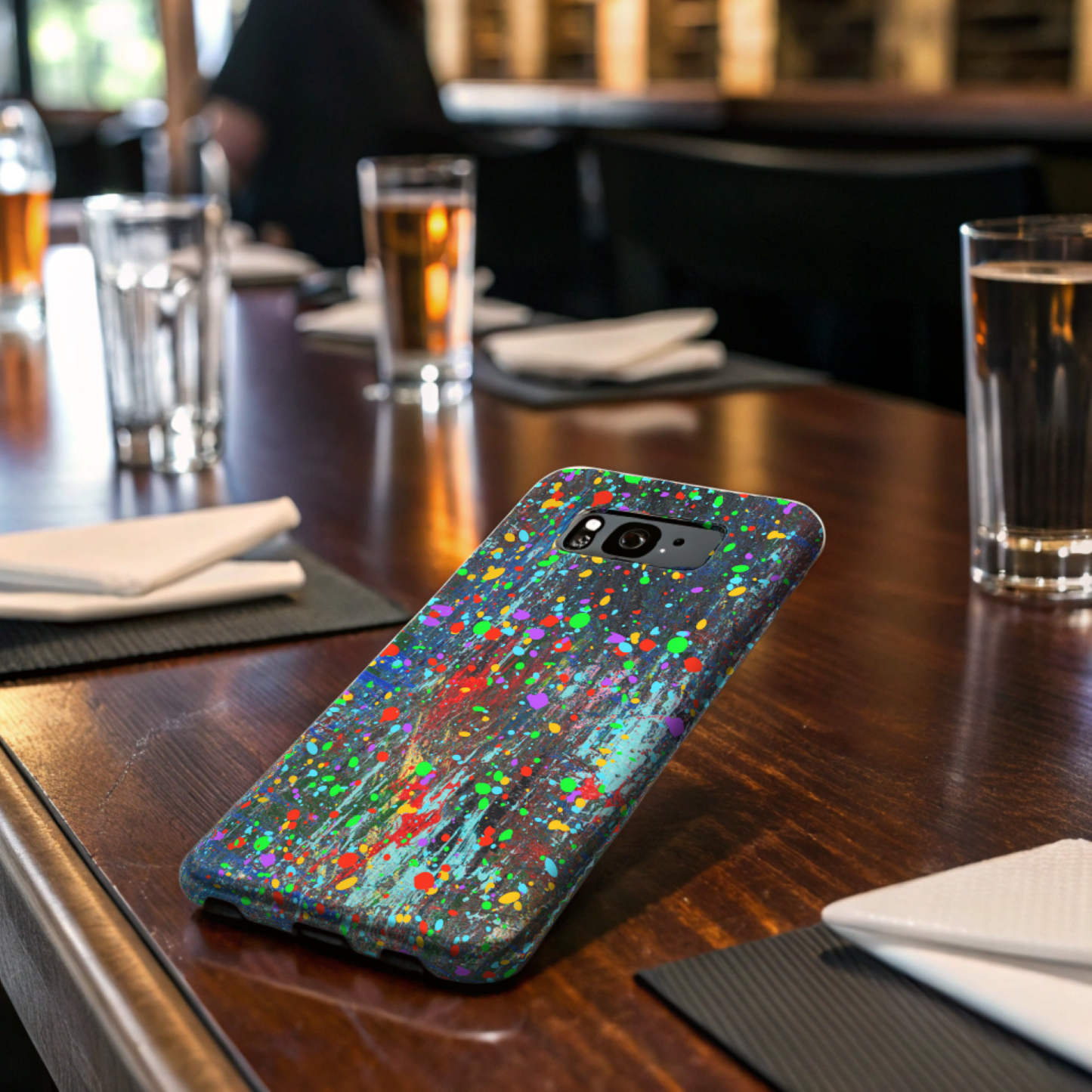 Printify colorful abstract drip paint phone case with vibrant multicolor splatter design on wooden table