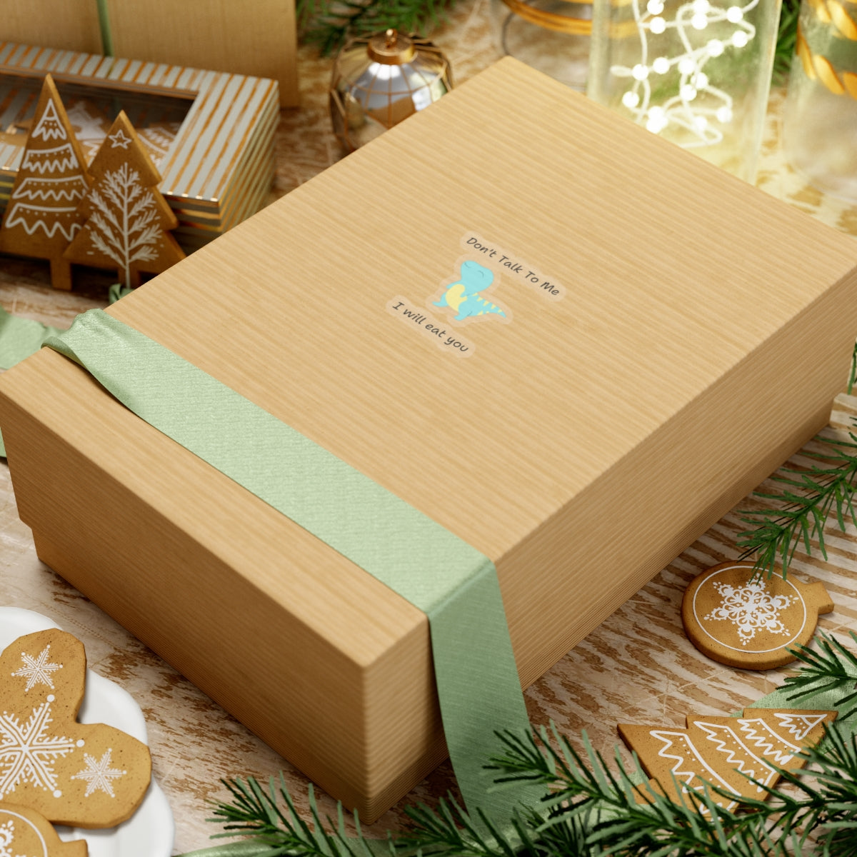 Do not talk to me funny cute dino sticker on a brown gift box with green ribbon surrounded by holiday decor