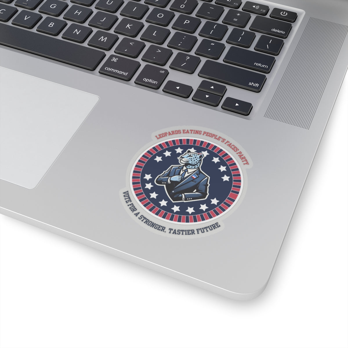 Funny political leopard face eating party sticker placed on silver laptop keyboard by Printify