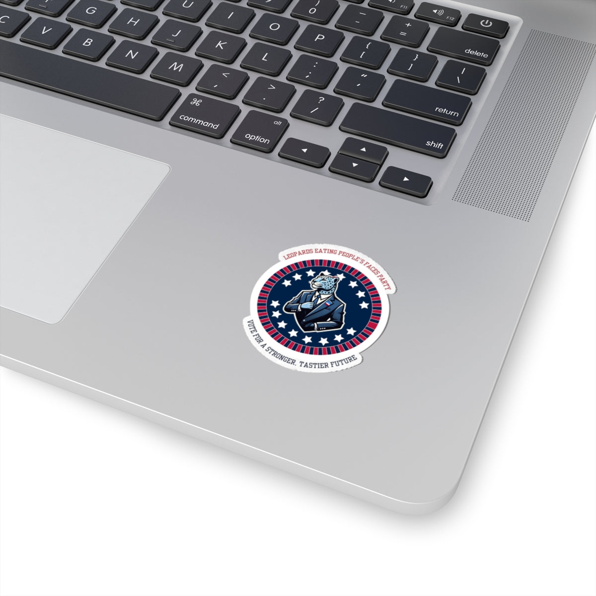 Funny political leopard face eating party sticker placed on silver laptop near keyboard