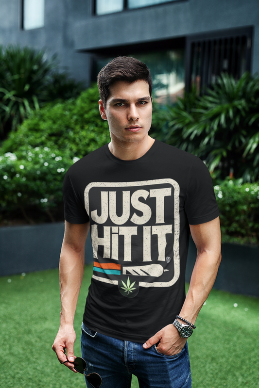 Male model wearing Printify black funny weed just do it meme t-shirt with JUST HIT IT weed leaf graphic outdoors