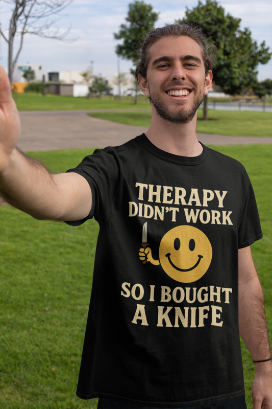 Smiling man outdoors wearing black shirt with yellow smiley holding knife and text therapy dark joke humor unisex t shirt .