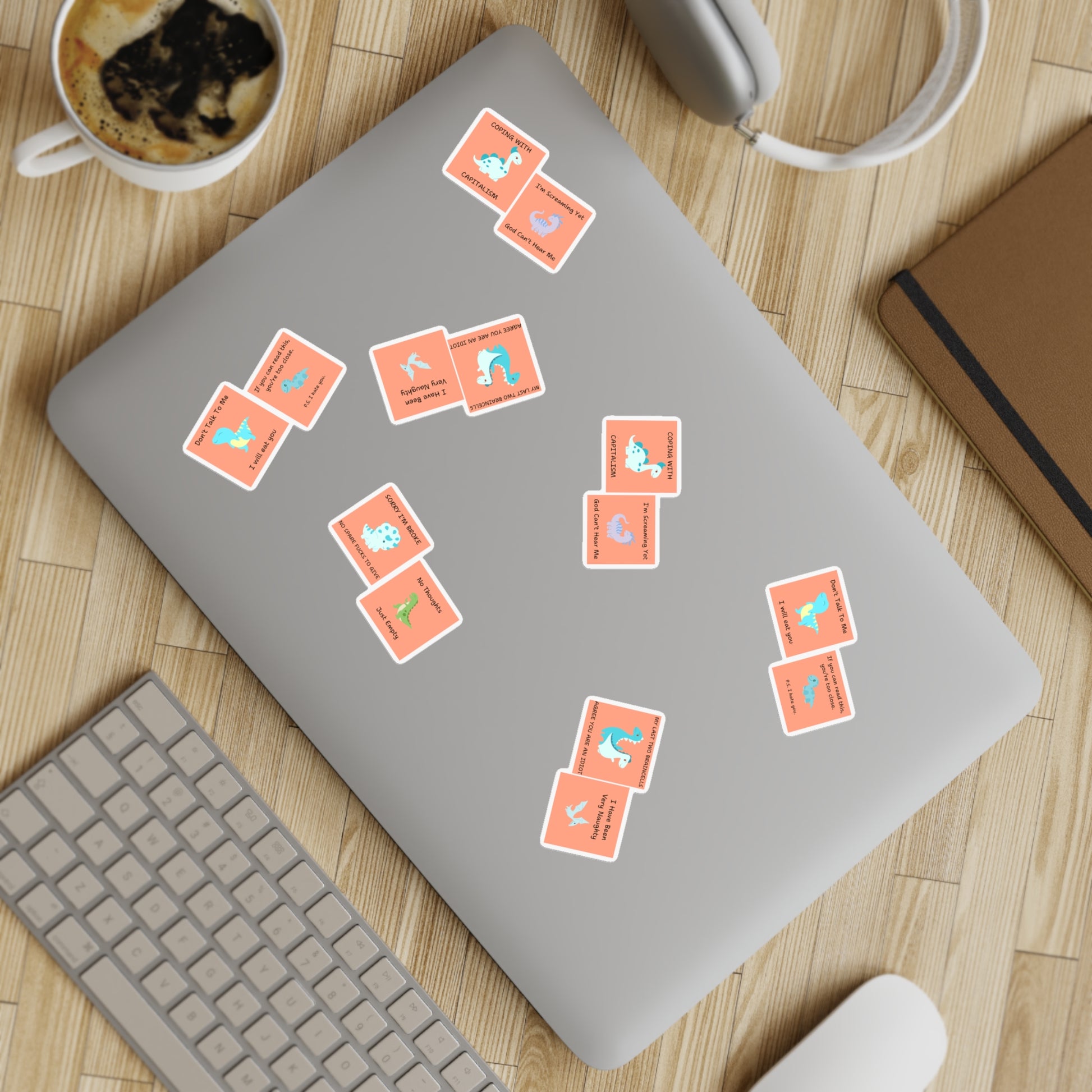 Colorful funny edgy sarcastic cute dino sticker bundle arranged on a laptop with coffee and accessories