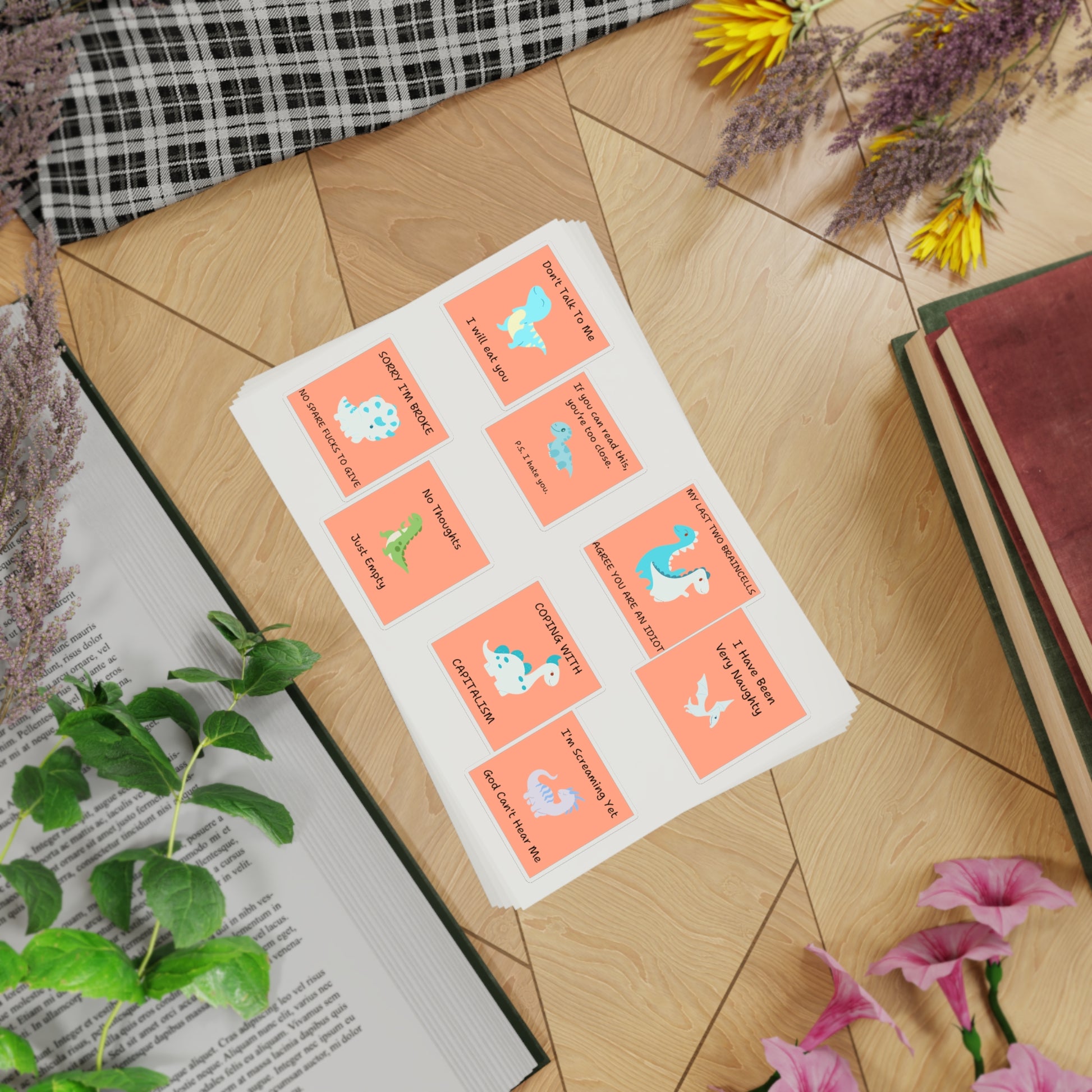 Funny edgy sarcastic cute dino sticker bundle on a wooden surface with plants and books