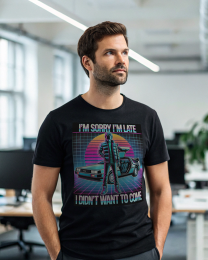A man stands in a modern office wearing the Printify Retro Graphic T-Shirt—featuring a helmeted figure by a car and the slogan, “I’M SORRY I’M LATE I DIDN’T WANT TO COME.” Ideal for pop culture fans.